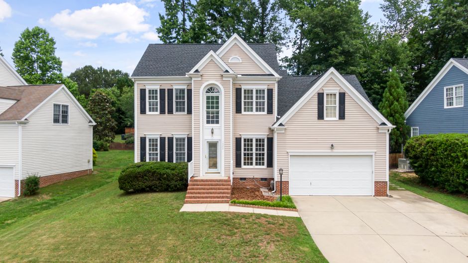 A two-story suburban home with white-framed windows, black shutters, and pale siding