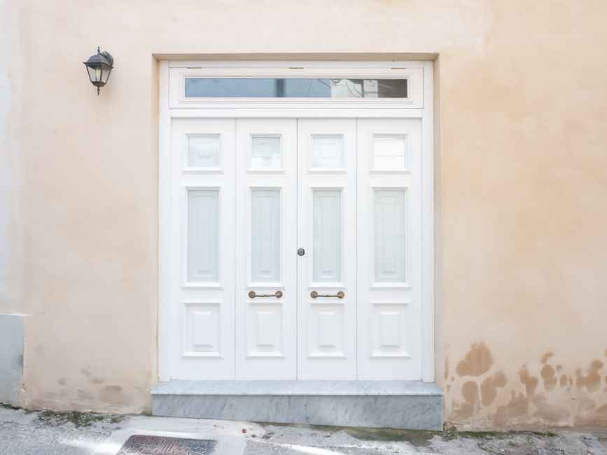 Professional storefront entrance showing white paneled double doors with glass transom