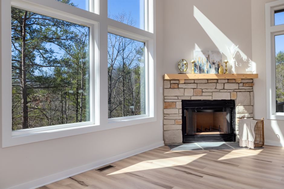 Bright living room with fireplace, large windows, and natural light streaming in